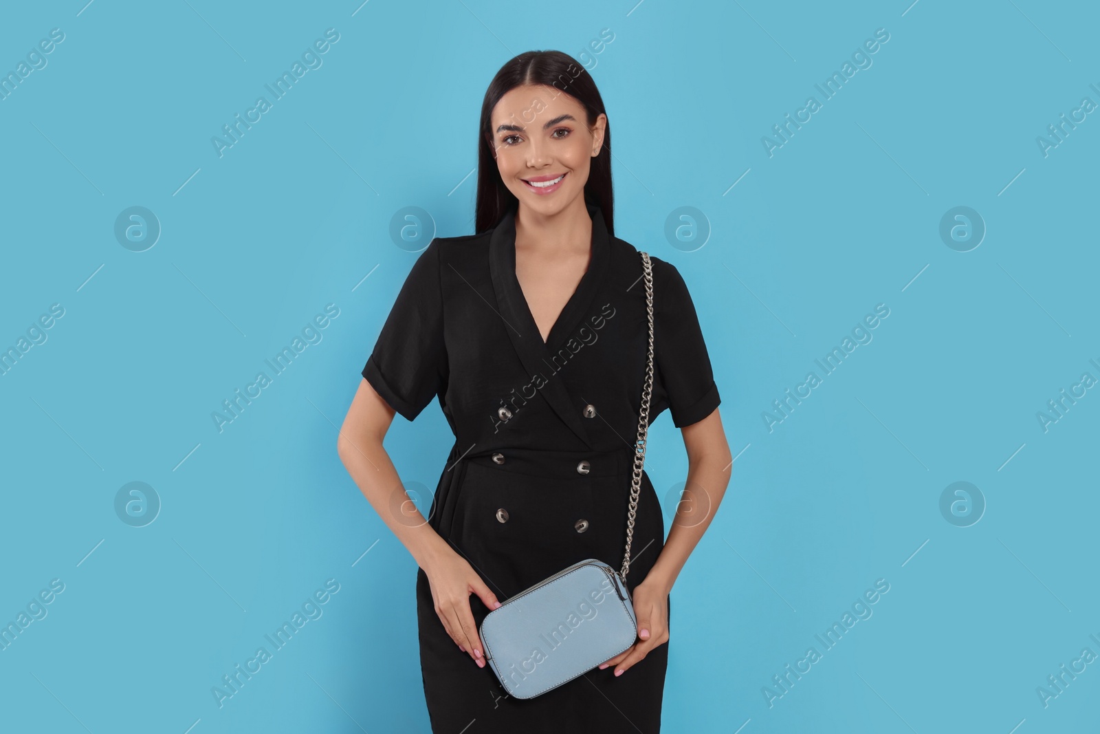 Photo of Beautiful young woman with stylish bag on light blue background