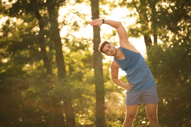 Young man doing exercise in park on sunny day