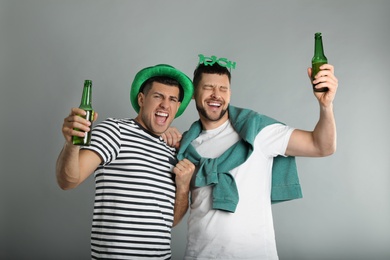 Photo of Emotional men in St Patrick's Day outfits with beer on light grey background