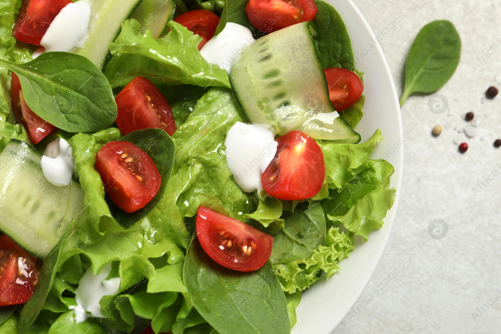 Photo of Delicious vegetable salad on light grey table, flat lay. Space for text