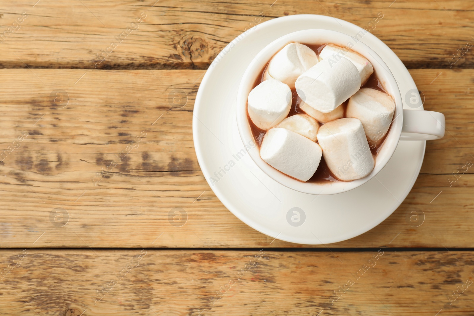 Photo of Tasty hot chocolate with marshmallows on wooden table, top view. Space for text