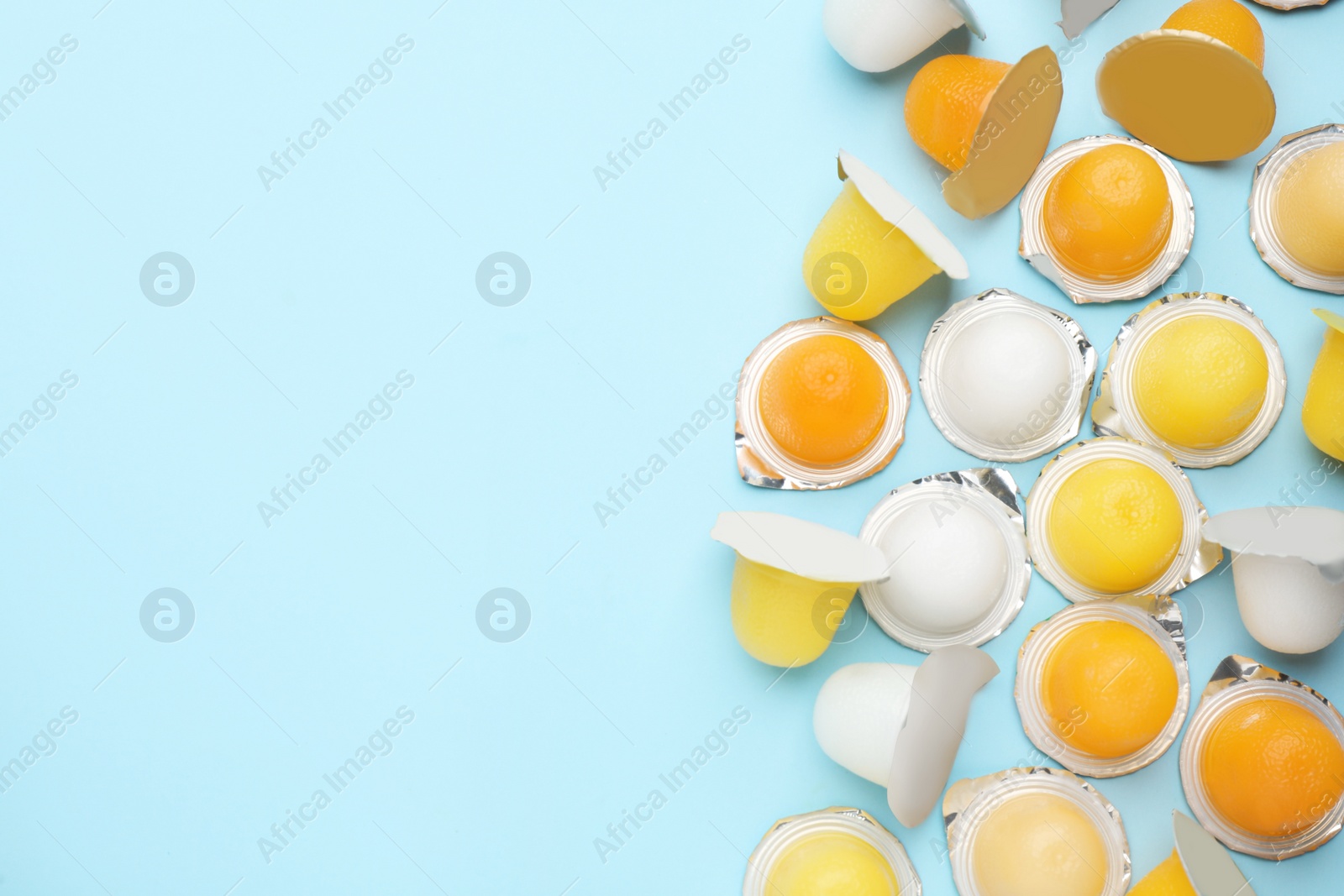 Photo of Tasty bright jelly cups on light blue background, flat lay. Space for text