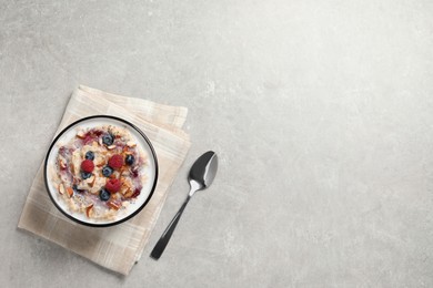 Photo of Tasty oatmeal porridge with toppings served on grey table, flat lay. Space for text