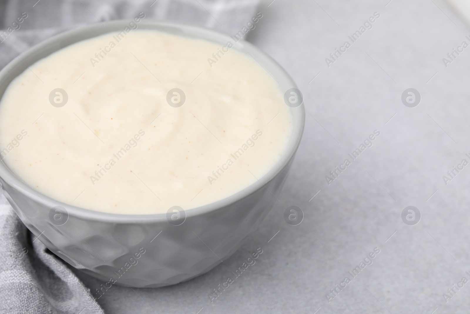 Photo of Delicious semolina pudding in bowl on light grey table, closeup. Space for text