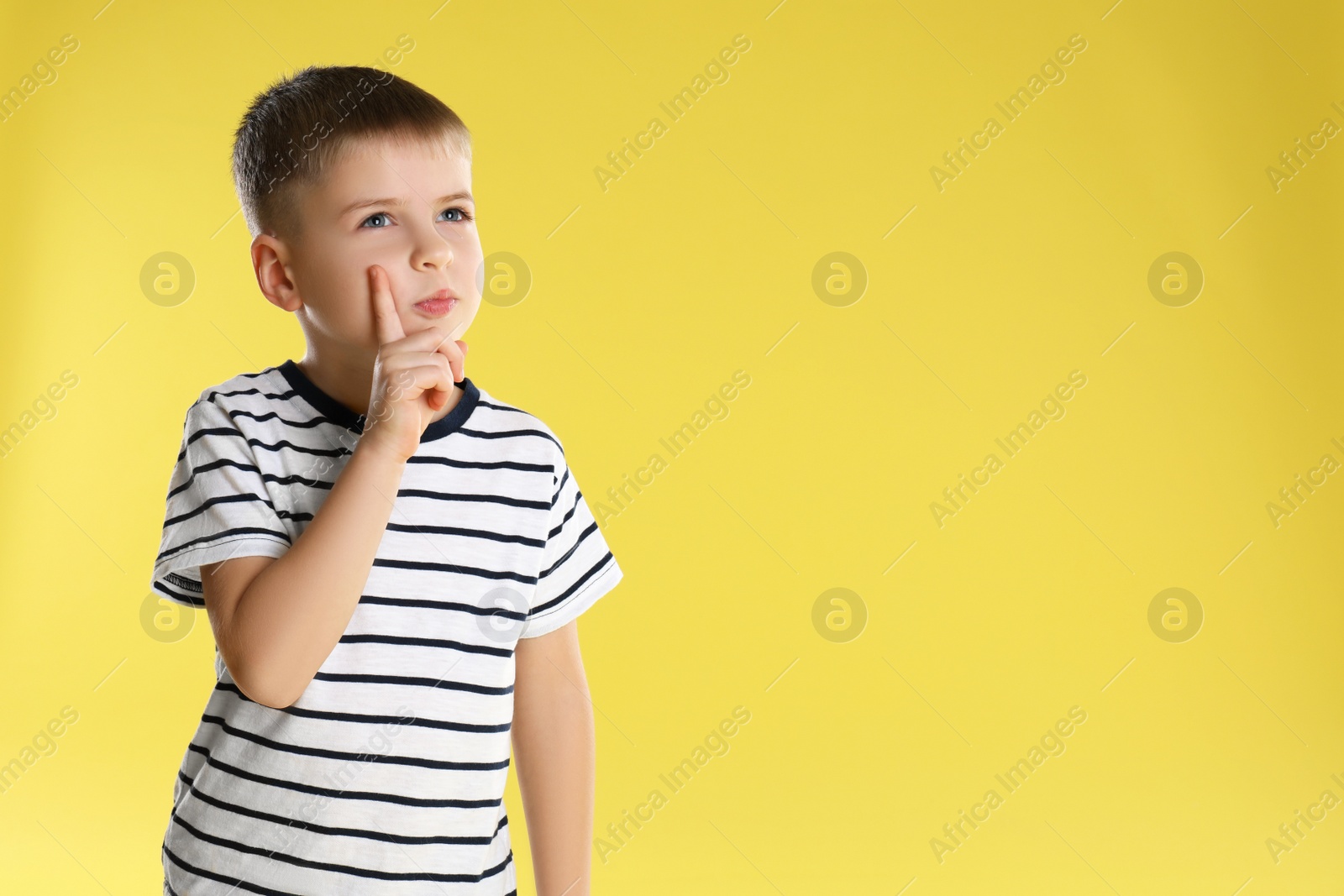 Photo of Portrait of little boy on yellow background. Space for text