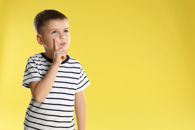 Portrait of little boy on yellow background. Space for text
