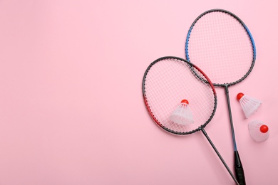 Photo of Rackets and shuttlecocks on pink background, flat lay with space for text. Badminton equipment
