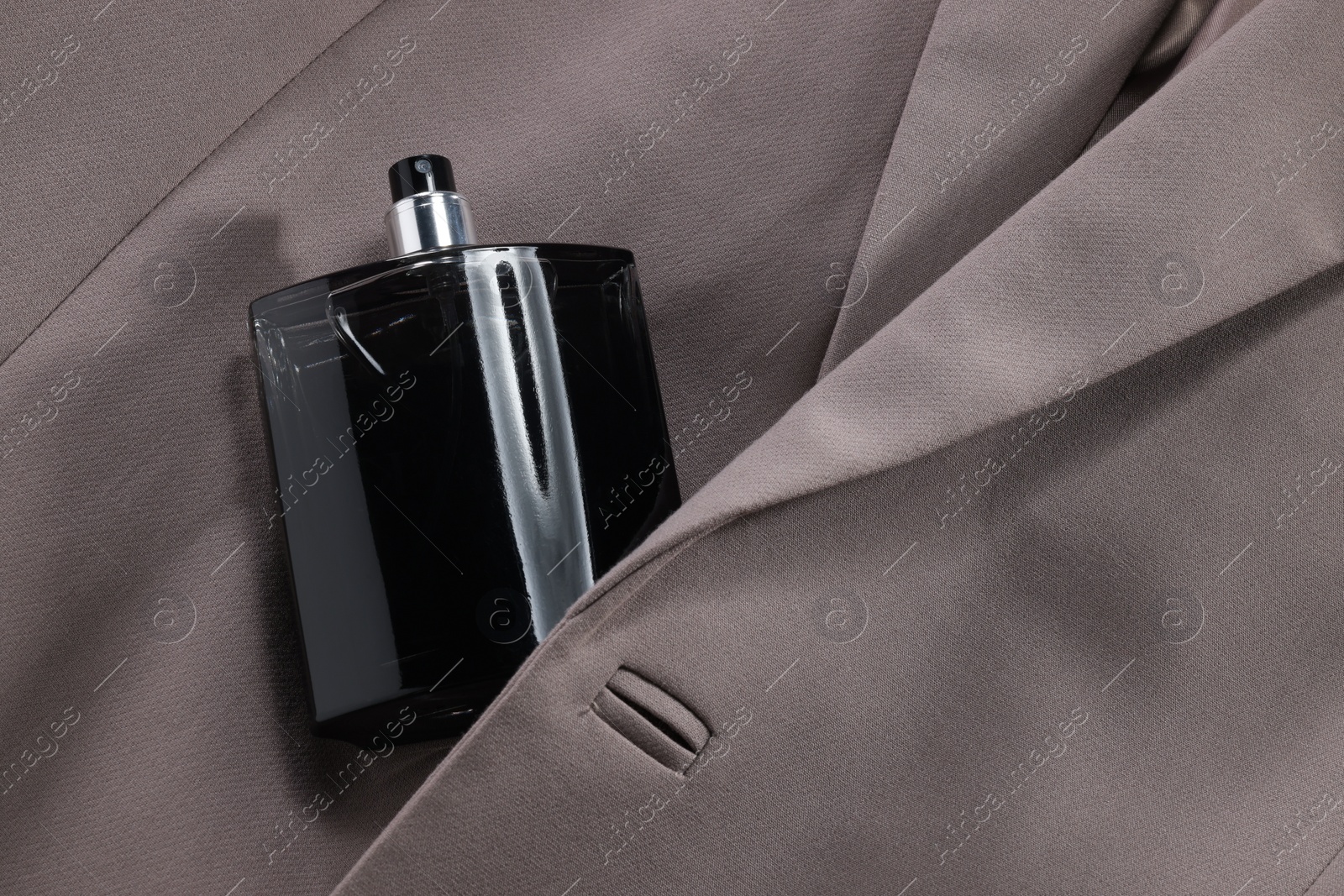Photo of Luxury men's perfume in bottle on beige jacket, above view. Space for text