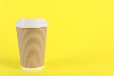 Photo of Paper cup with plastic lid on yellow background, space for text. Coffee to go