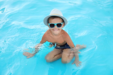 Photo of Cute little boy in outdoor swimming pool