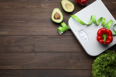 Flat lay composition with bathroom scale and measuring tape on wooden floor, space for text. Weight loss concept