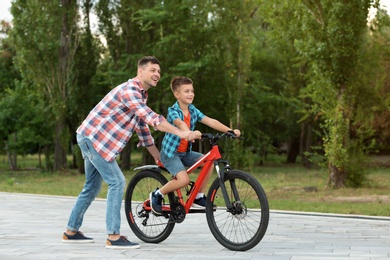 Photo of Dad teaching son to ride bicycle in park