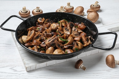 Frying pan with mushrooms on wooden table