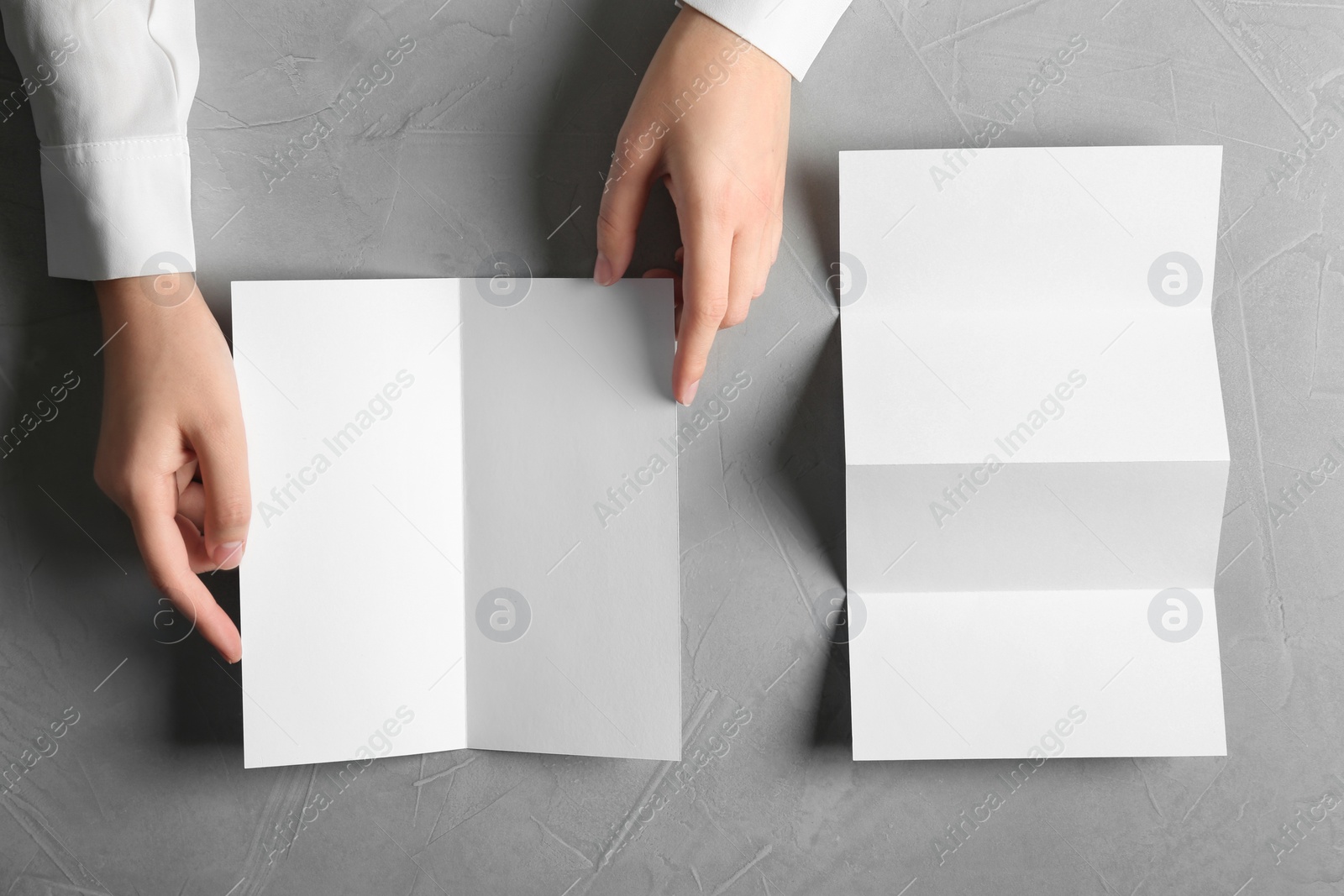 Photo of Woman with blank brochures on grey background, top view. Mockup for design