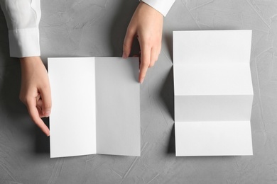 Photo of Woman with blank brochures on grey background, top view. Mockup for design