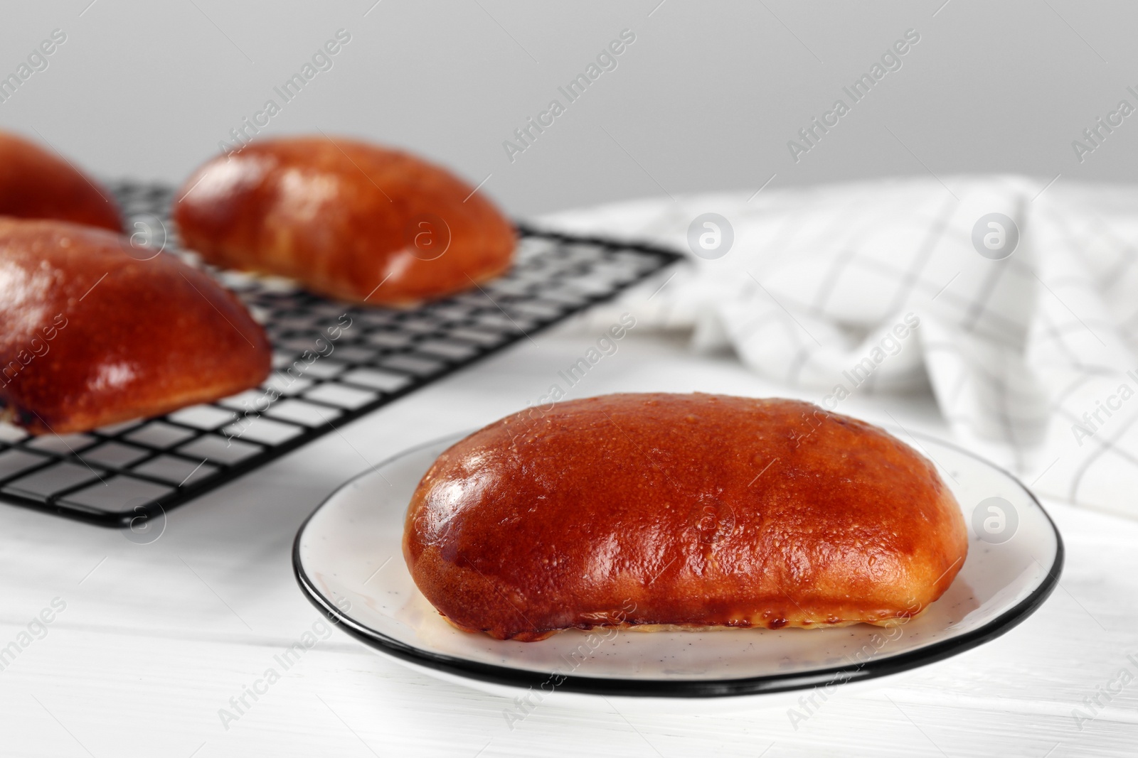 Photo of Delicious baked pirozhki on white wooden table, closeup