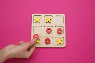 Photo of Woman playing tic tac toe game on bright pink background, top view