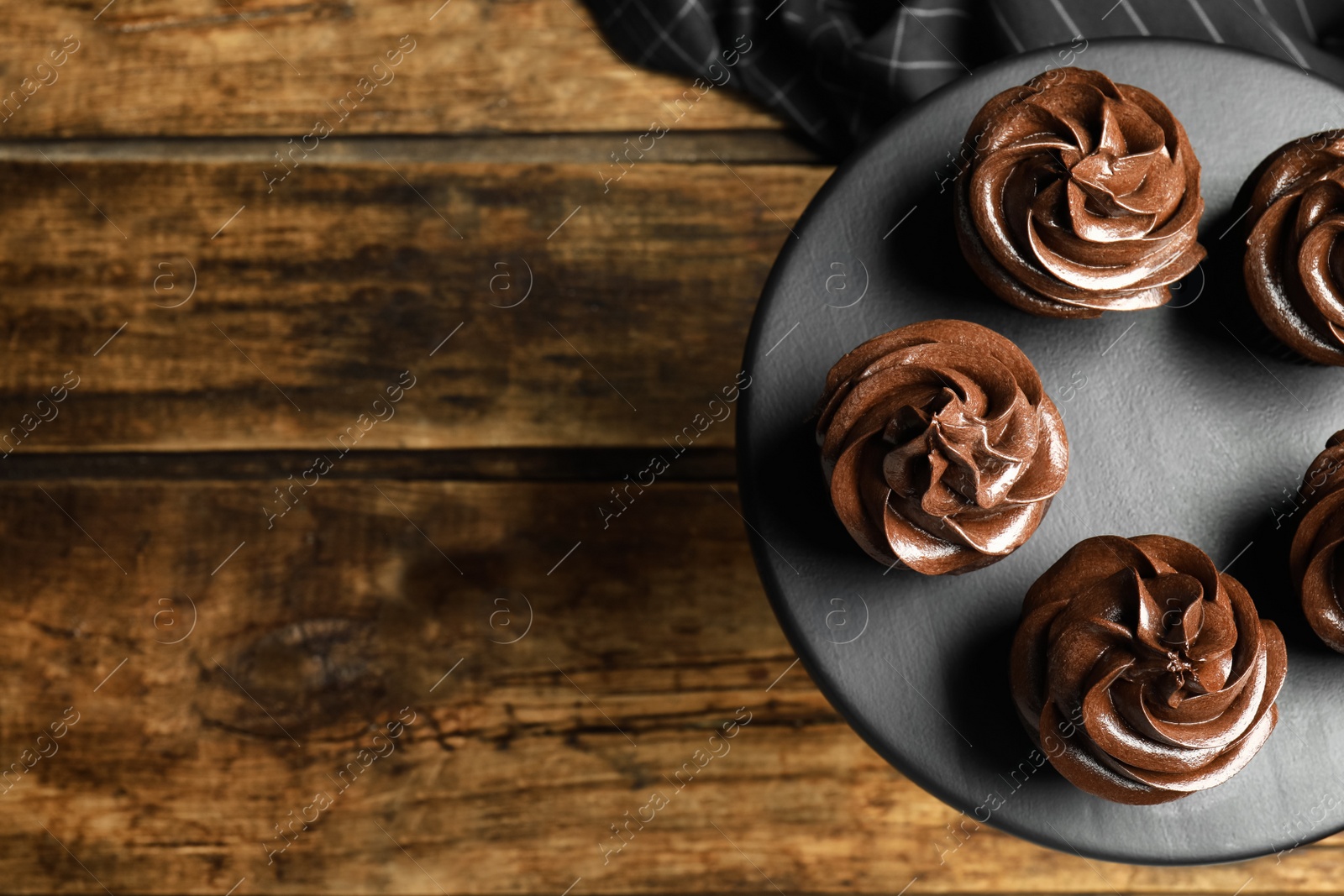 Photo of Dessert stand with delicious chocolate cupcakes on wooden table, top view. Space for text