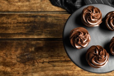 Dessert stand with delicious chocolate cupcakes on wooden table, top view. Space for text