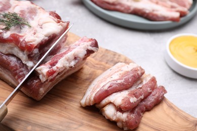 Photo of Cutting fresh pork fatback on grey table, closeup