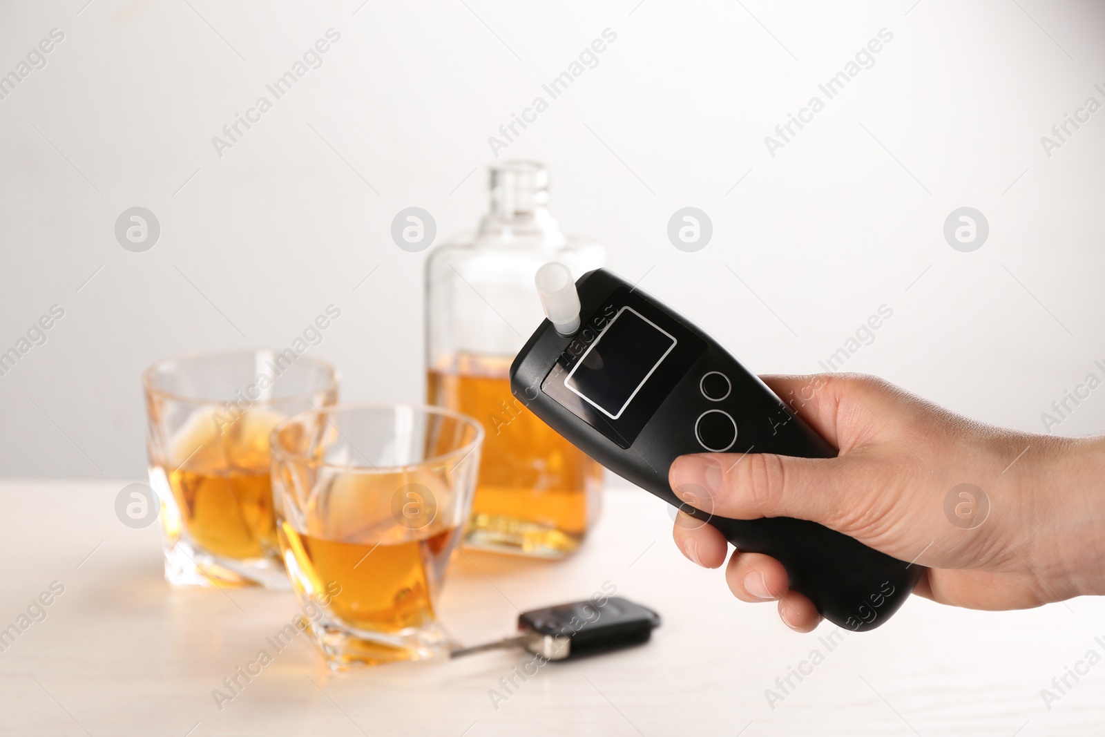 Photo of Woman holding modern breathalyzer with blank screen at wooden table, closeup