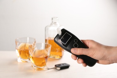 Photo of Woman holding modern breathalyzer with blank screen at wooden table, closeup
