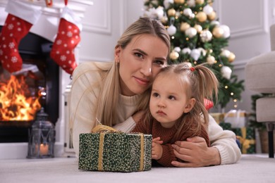 Happy mother and her daughter with Christmas gift in festively decorated room