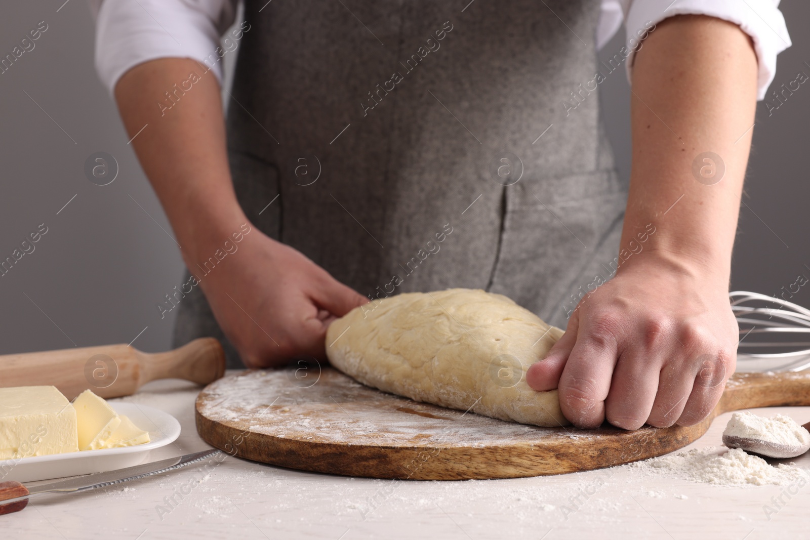 Photo of Man kneading dough at table near grey wall, closeup