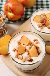 Photo of Delicious yogurt with fresh peach and granola on white table, above view