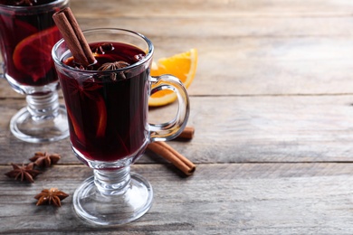 Photo of Delicious red mulled wine on wooden table. Space for text
