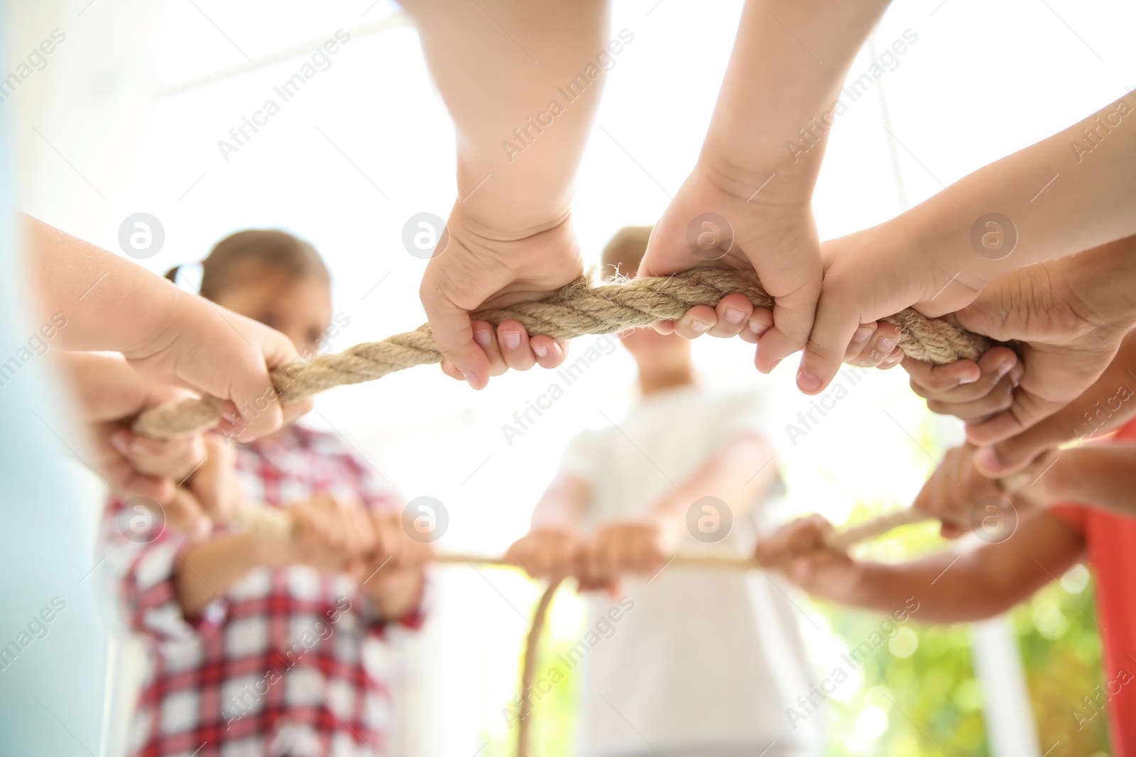 Photo of Little children holding rope on light background, focus on hands. Unity concept