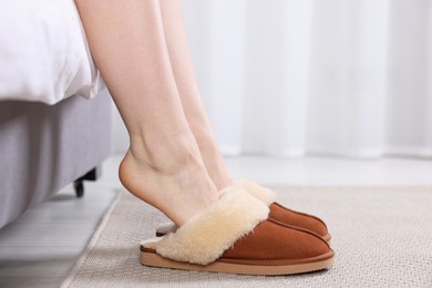 Photo of Woman in brown soft slippers at home, closeup. Space for text