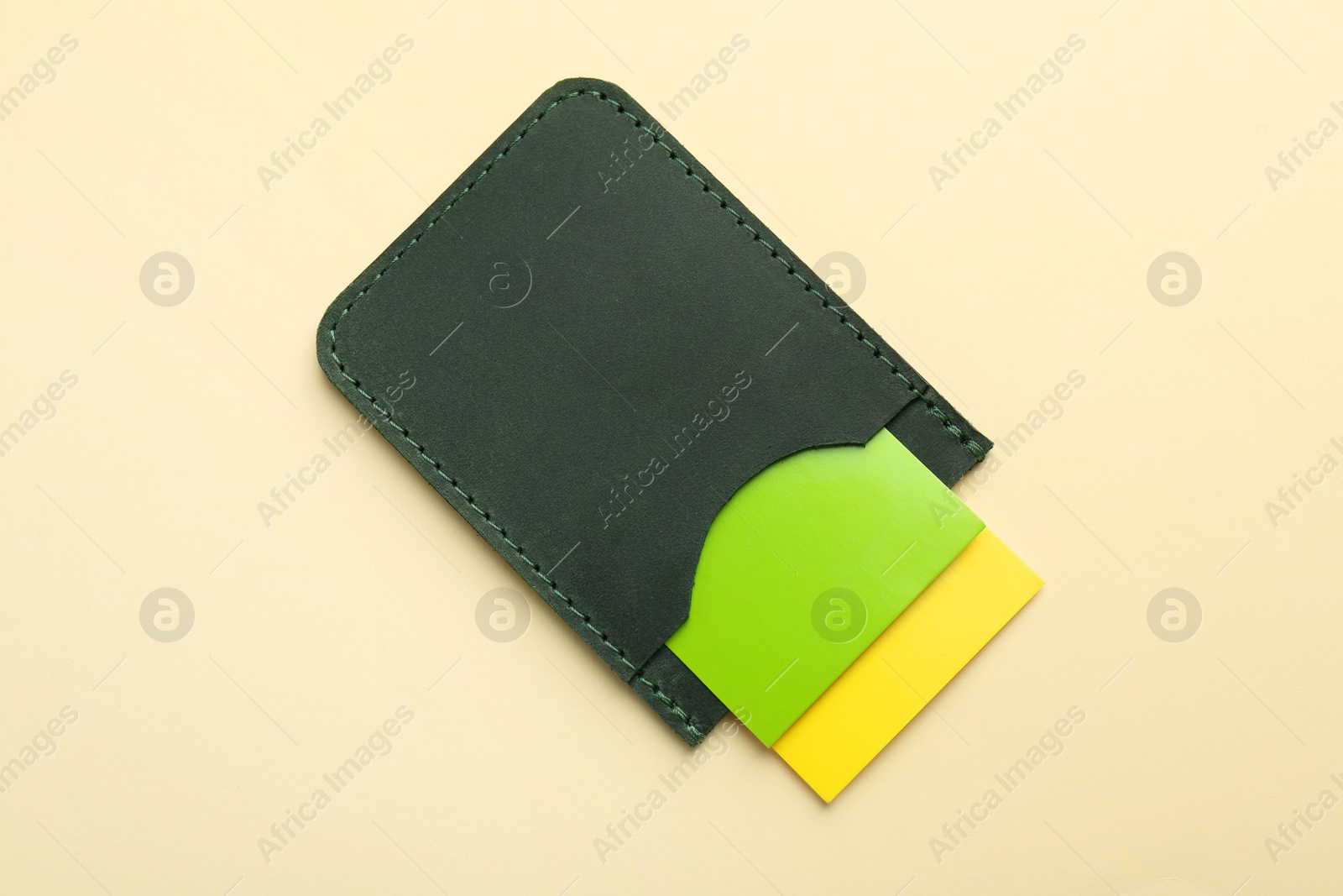 Photo of Leather business card holder with colorful cards on beige background, top view