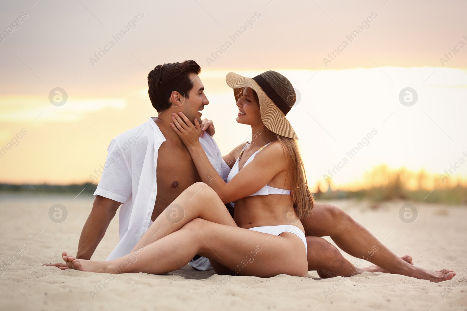 Photo of Happy young couple relaxing together on sea beach at sunset