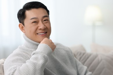 Photo of Portrait of smiling man on sofa indoors. Space for text