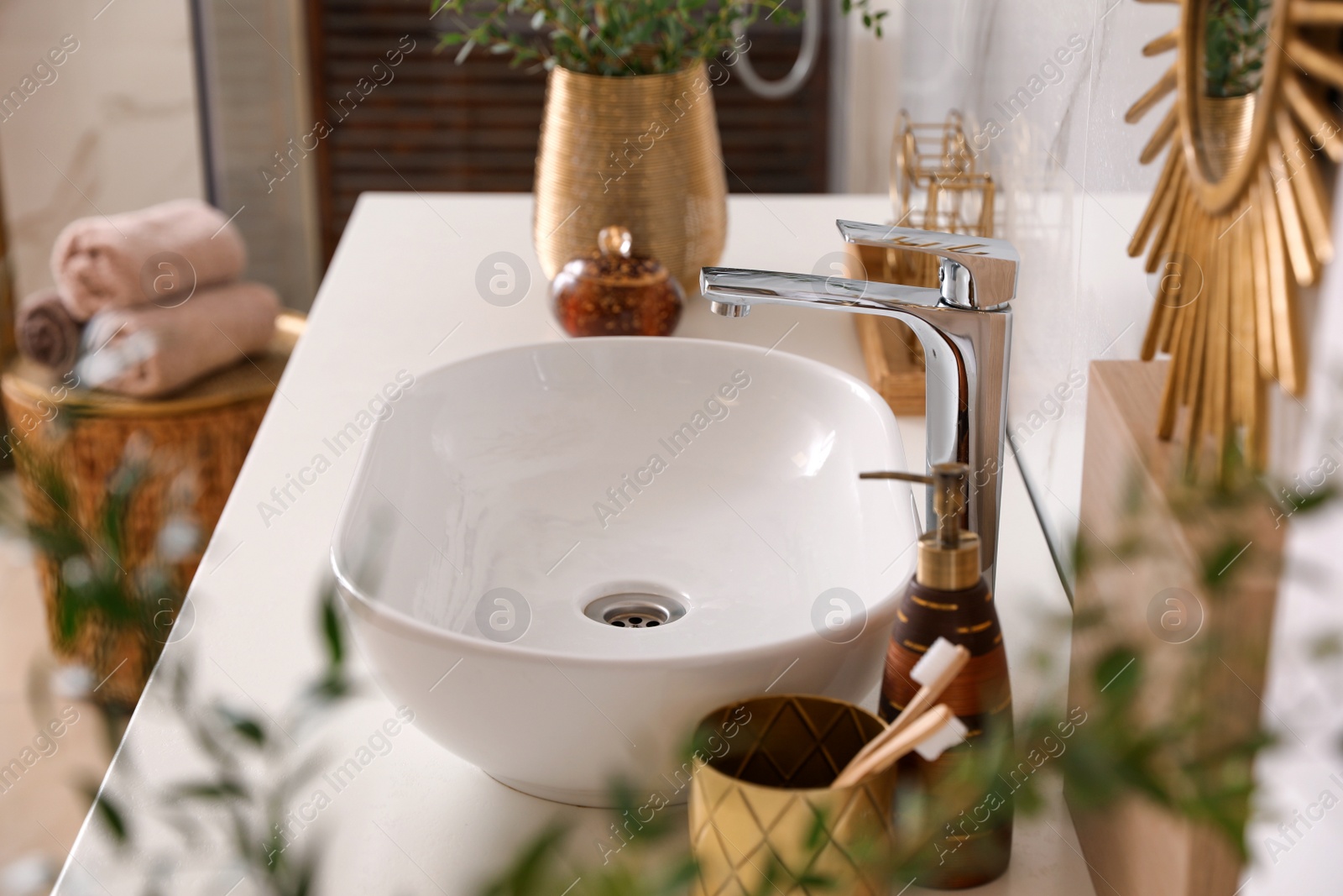 Photo of Vase with beautiful branches and toiletries near vessel sink in bathroom. Interior design