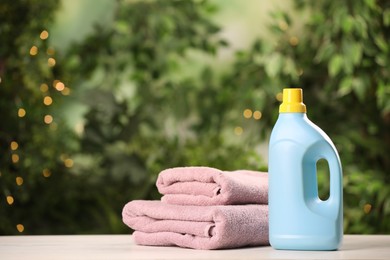 Detergent and clean towels on white wooden table outdoors, space for text. Laundry day