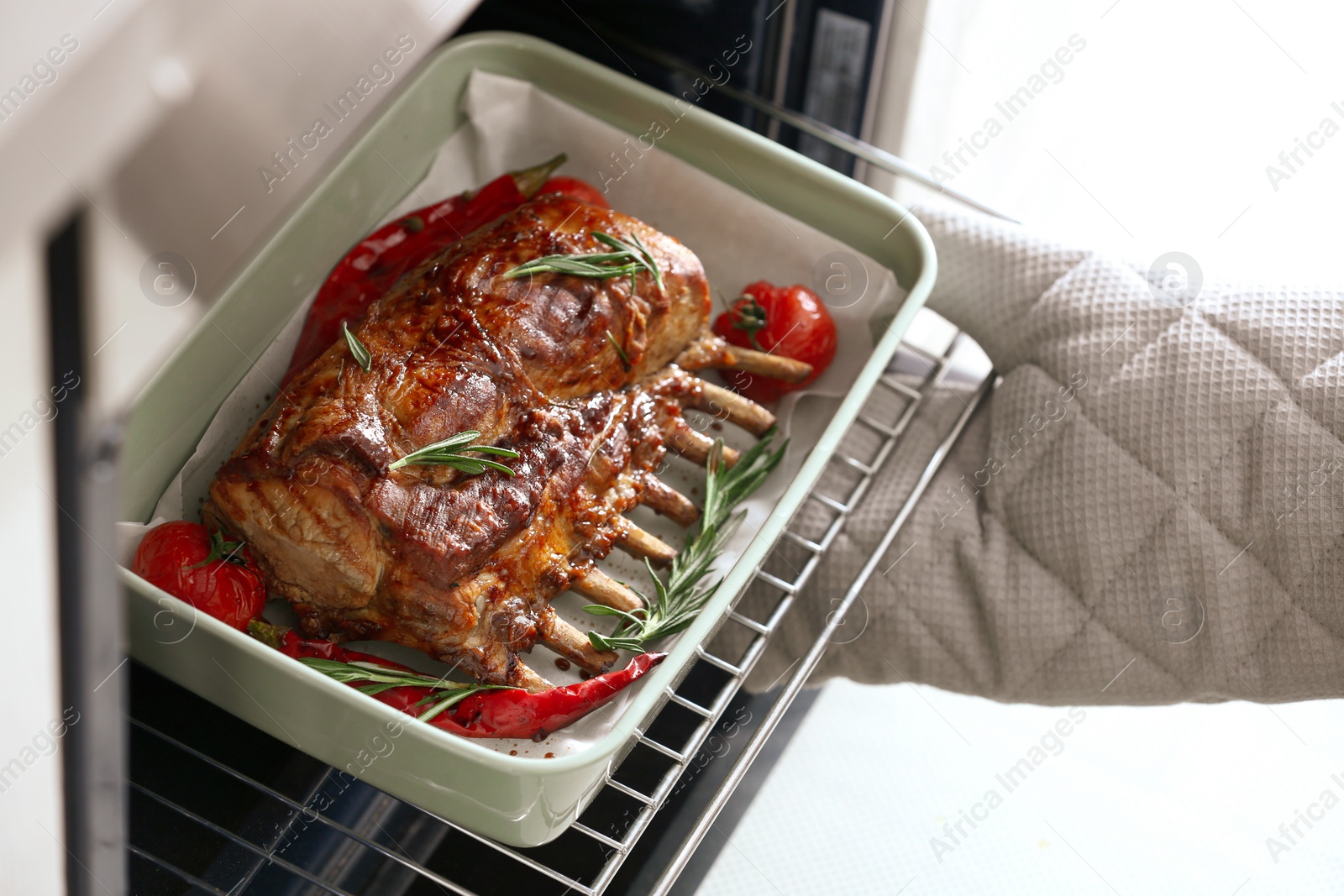 Photo of Chef taking delicious roasted ribs out of oven, closeup