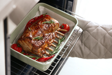 Photo of Chef taking delicious roasted ribs out of oven, closeup