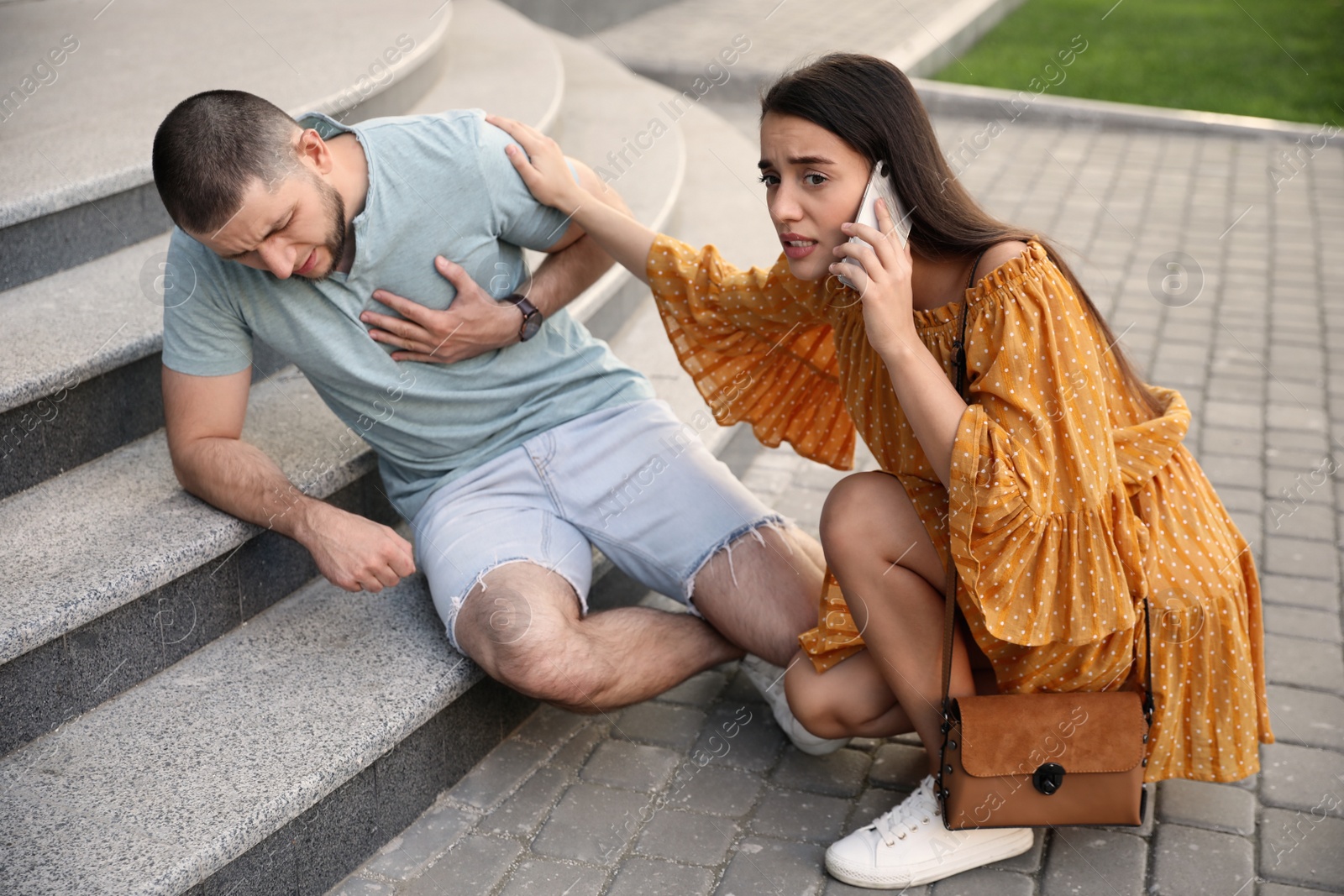 Photo of Woman calling ambulance to help man with heart attack on stairs