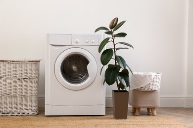 Photo of Laundry room interior with modern washing machine and wicker basket near white wall