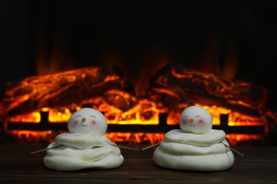 Photo of Cute decorative snowmen on wooden floor near fireplace