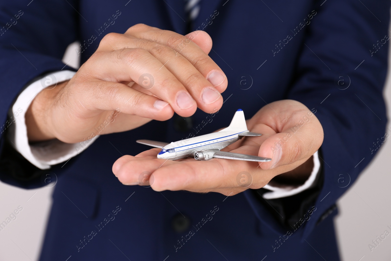 Photo of Insurance agent covering toy plane on grey background, closeup. Travel safety concept