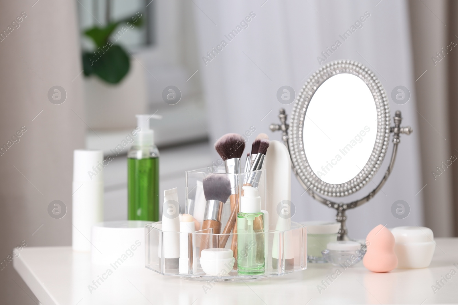 Photo of Cosmetic products and makeup accessories on table against blurred background