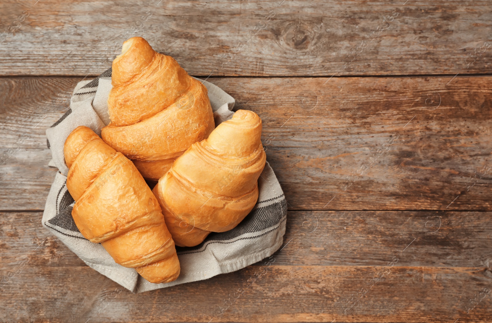 Photo of Tasty croissants on wooden background, top view