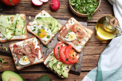 Different delicious sandwiches with microgreens on wooden table, flat lay