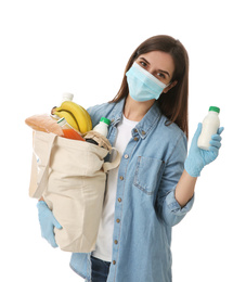Photo of Female volunteer in protective mask and gloves with products on white background. Aid during coronavirus quarantine
