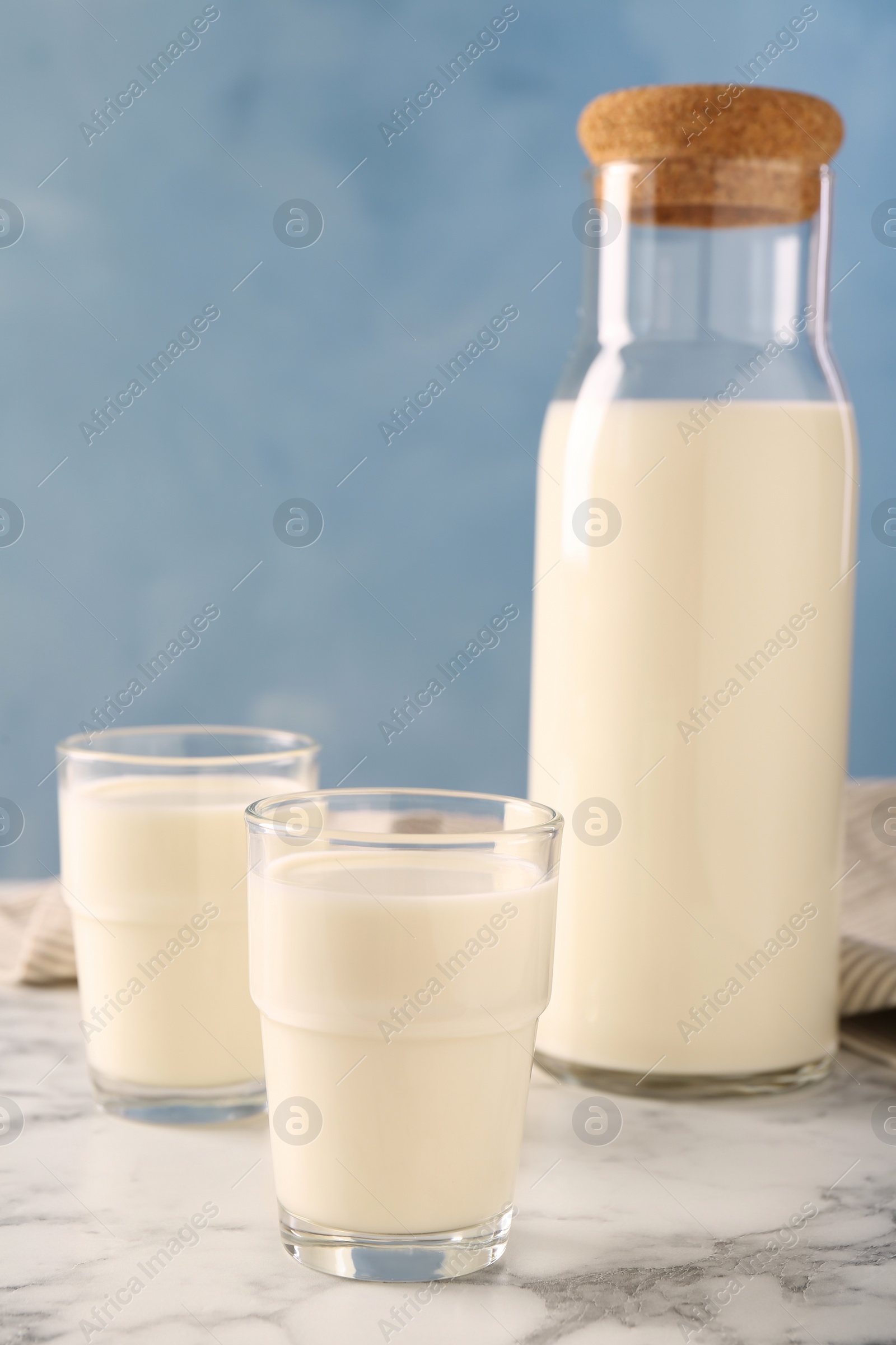 Photo of Carafe and glass of fresh milk on white marble table