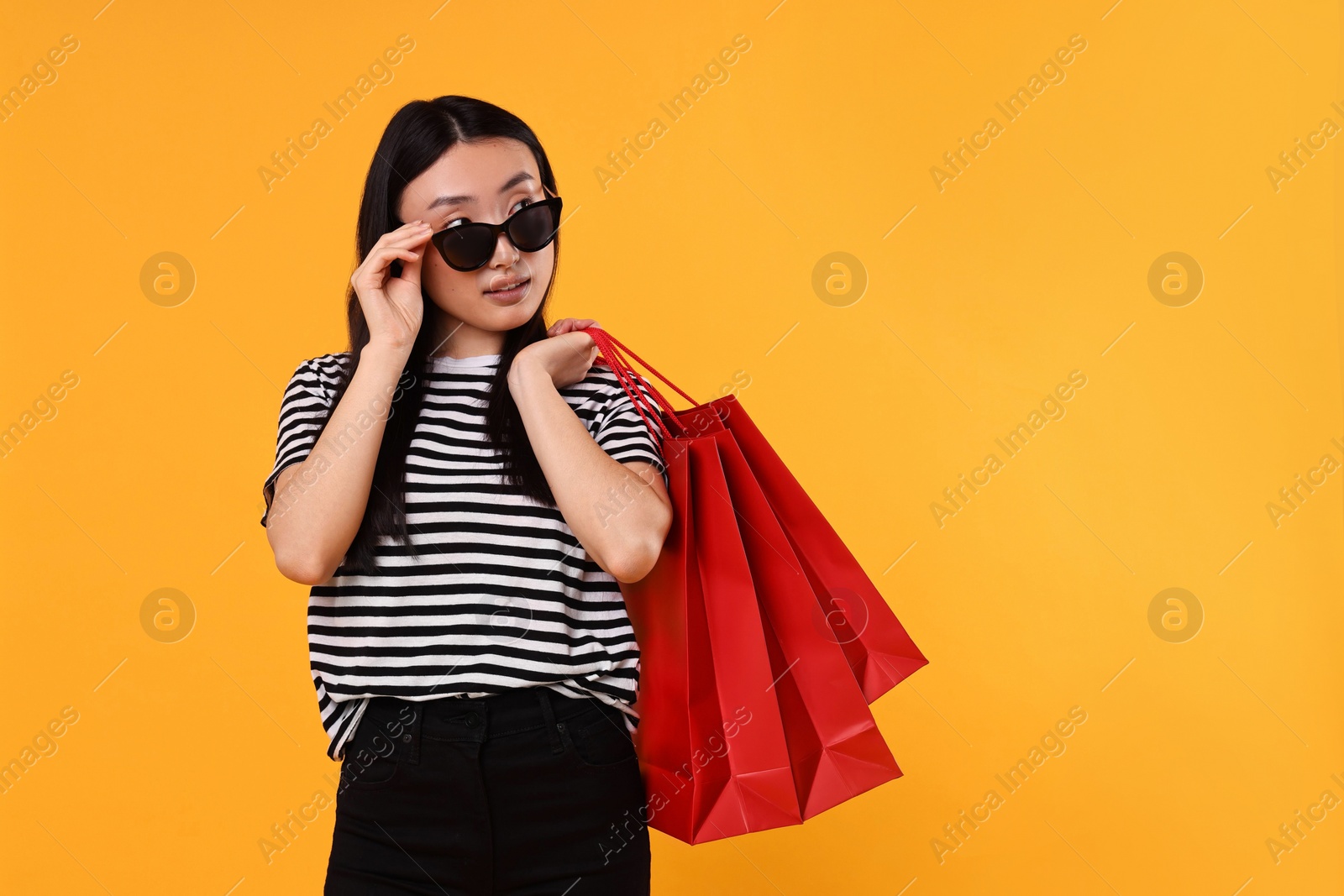 Photo of Beautiful woman with shopping bags on yellow background. Space for text