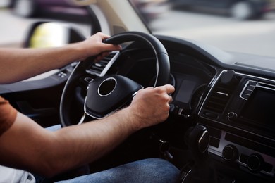 Photo of Man driving his car, closeup view of hands on steering wheel